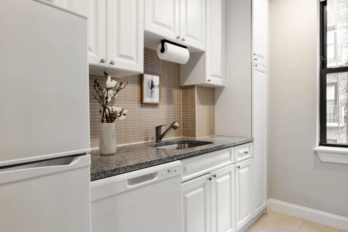 Kitchen with white cabinets, granite countertop, sink, a white refrigerator and dishwasher.