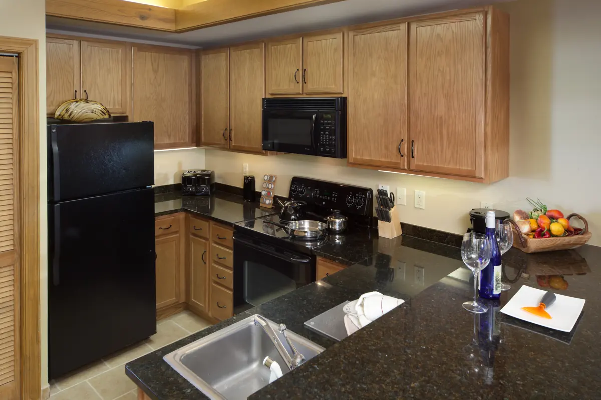 Similar room (illustrative): kitchen with wooden cabinets, black appliances, a dark countertop and a stainless sink.