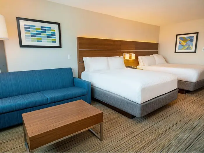 Suite with two queen beds and blue sofa.