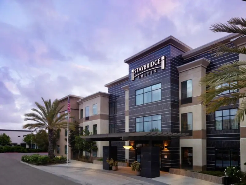 Hotel building at dusk with a Staybridge Suites sign and palm trees.