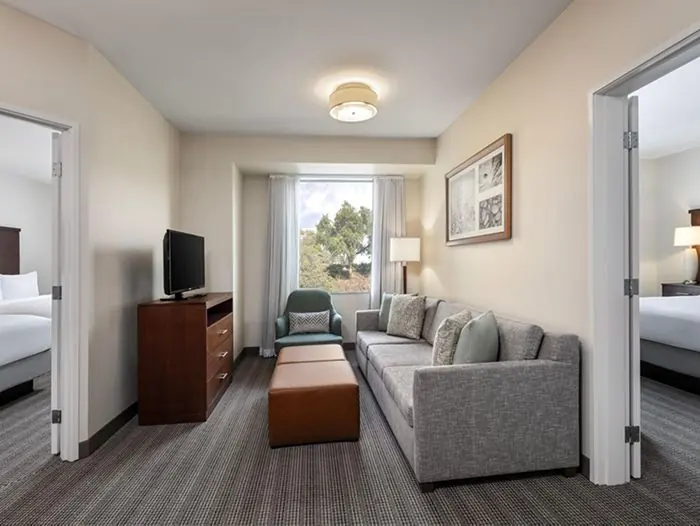 Living room with sofa and TV, doors to two bedrooms on each side.