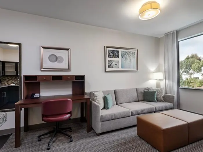 Living area with sofa, ottoman and desk.