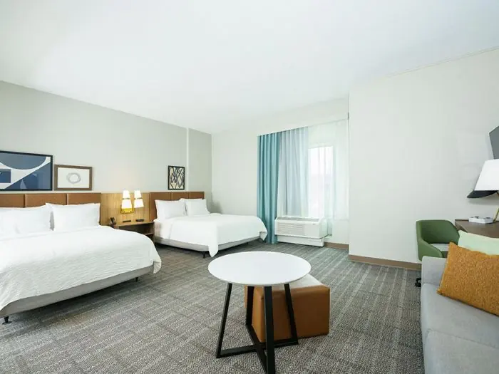 Studio with two queen beds, sofa and round table.
