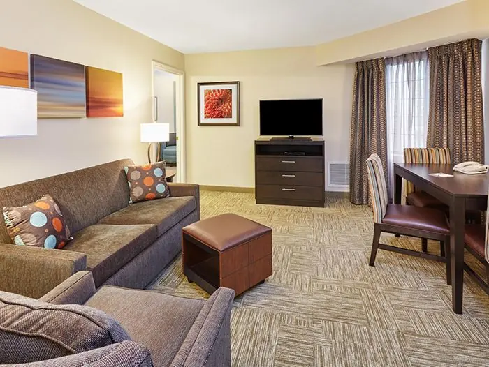 Living room with sofa, ottoman, TV and dining table.