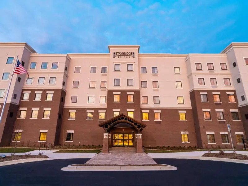 Five-story brick hotel building with an entrance canopy and an American flag.
