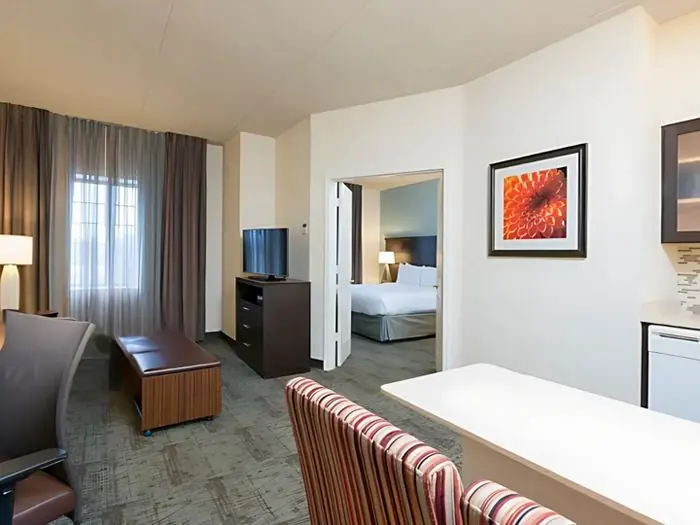 Living area with sofa chairs, open door to bedroom with bed.