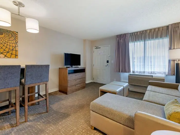 Living/dining area with sectional sofa, bar stools and TV.
